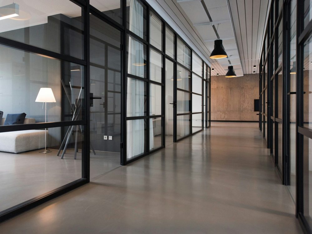 A modern law office interior with glass-walled meeting rooms, a lounge seating area and warm timber panelling